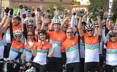 Image is of a group of cheering participants at a cycle for sight event