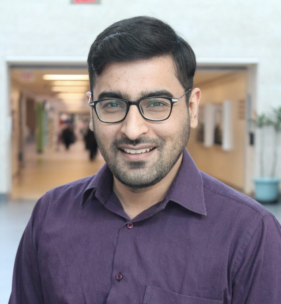 Photo of Ali Usman. Ali is in a purple button-down shirt and is smiling at the camera.