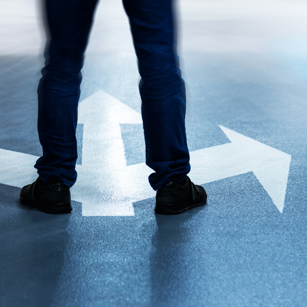 Man's legs on the road with three arrows pointing in different directions