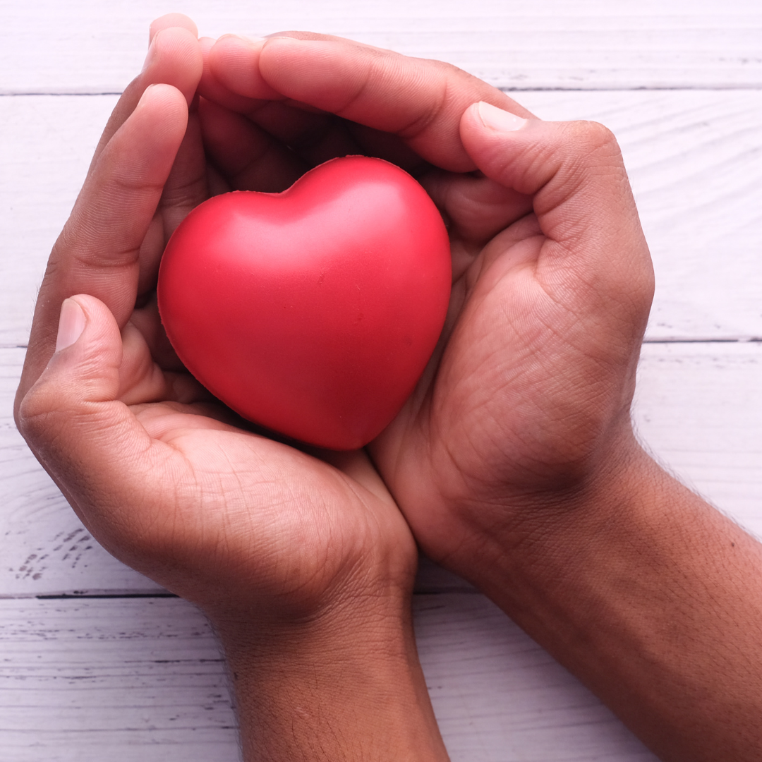 A red heart shaped object in someone's hands