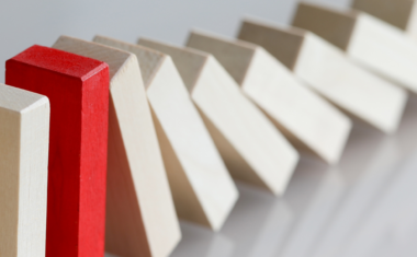 One red domino among other cream-coloured dominos